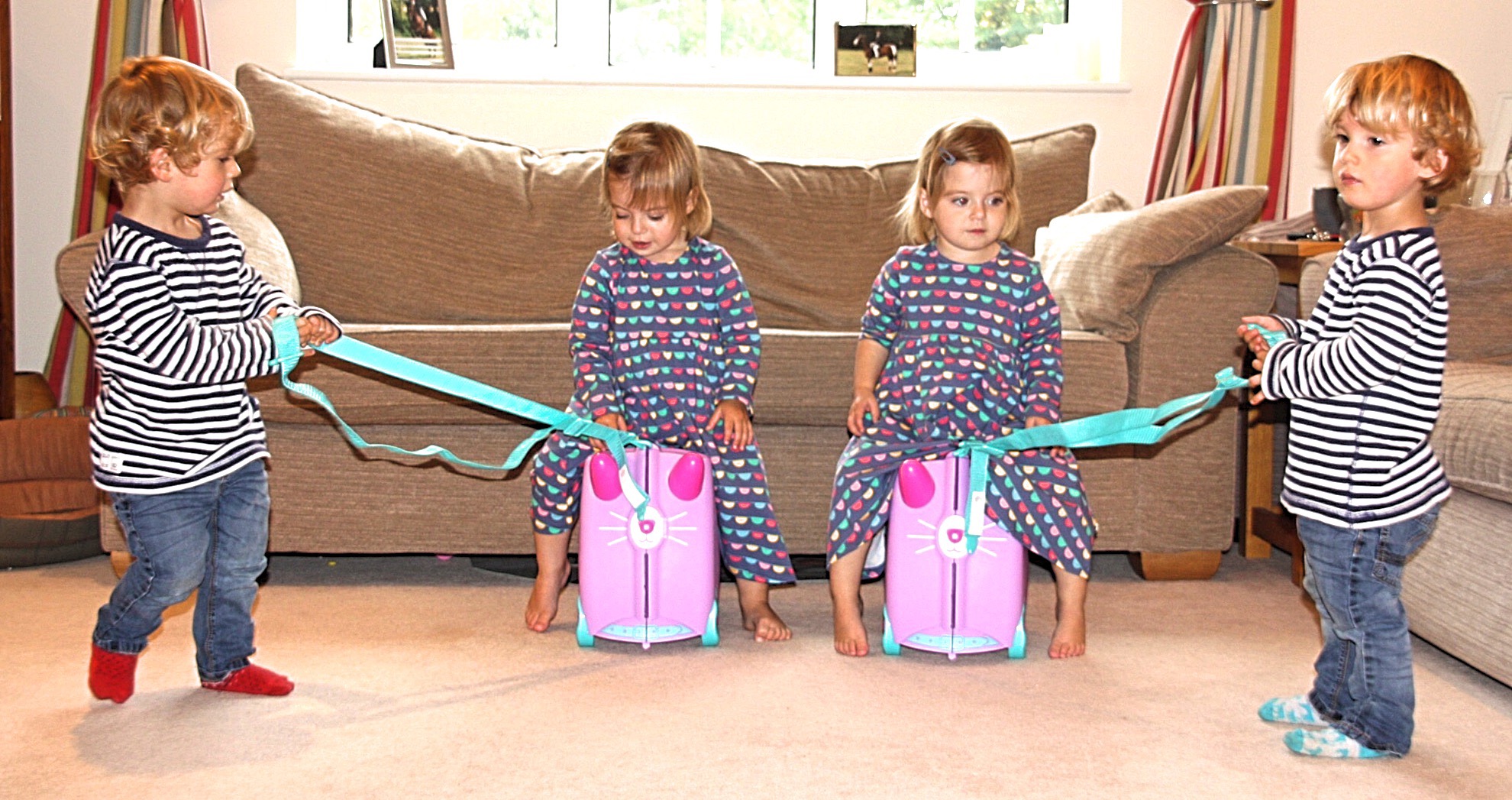 two sets of twins pulling Trunki travel cases across the floor