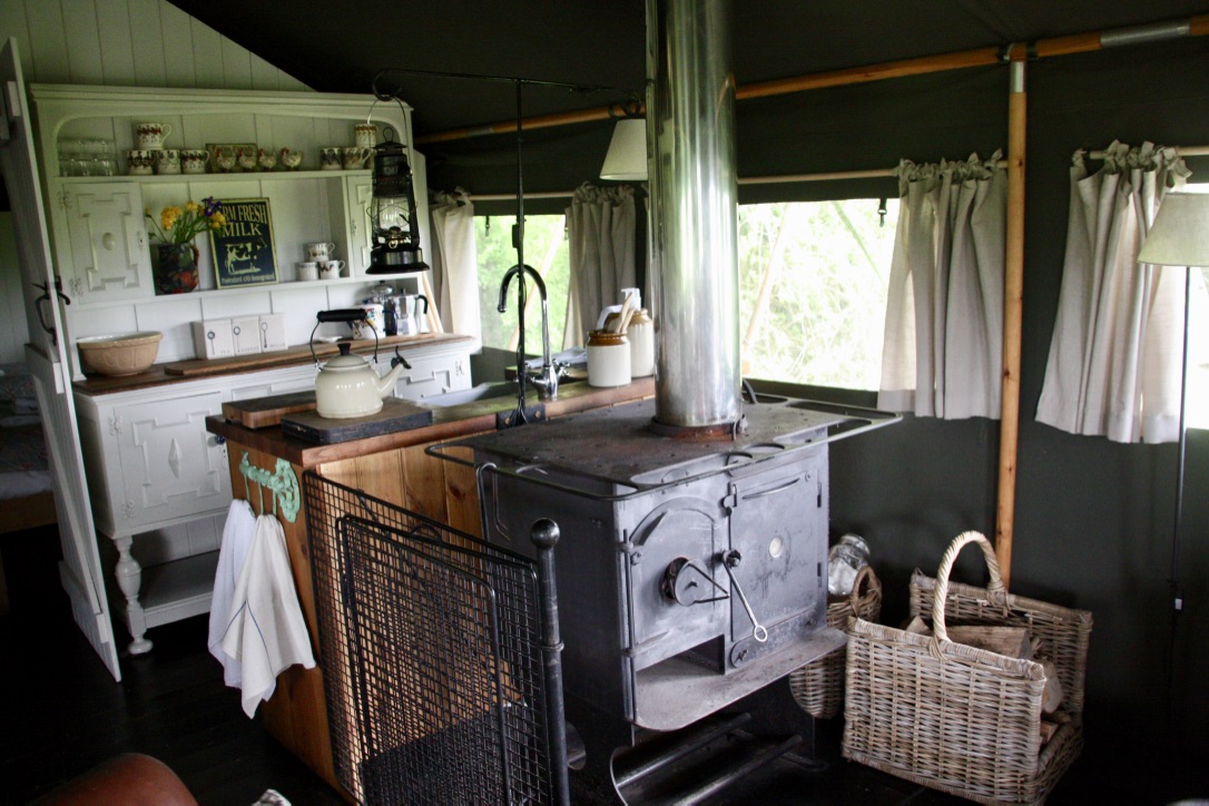 The living space at the Dandelion Hideaway showing the leather sofa, farmhouse wooden table, stove cooking range and fresh flowers on the table.