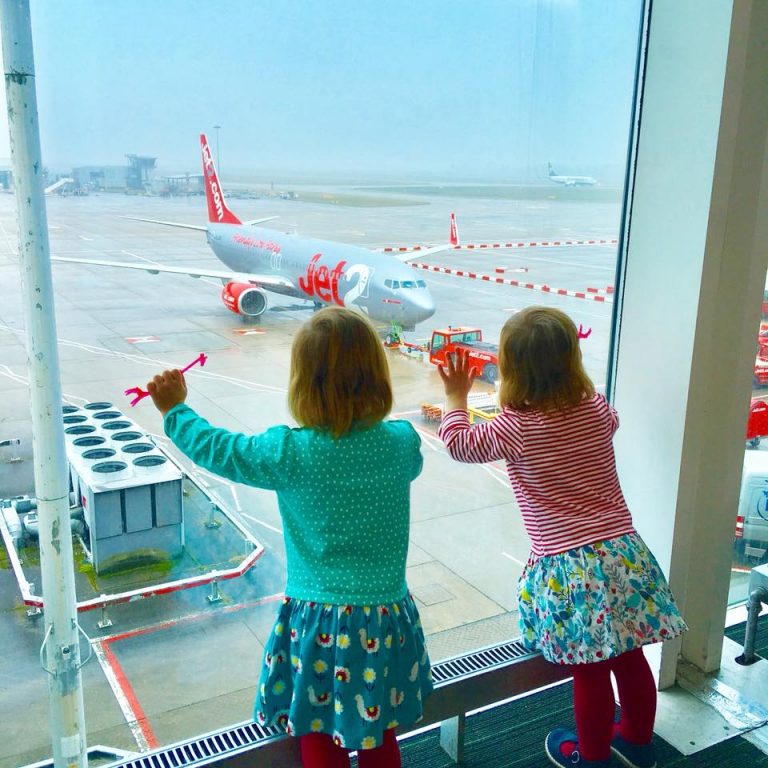 Twins at the airport looking out at the airplane