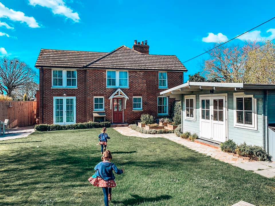 UK holidays with toddlers Garden view of Spindle cottage with children running through the garden. A family friendly cottage in the New Forest.