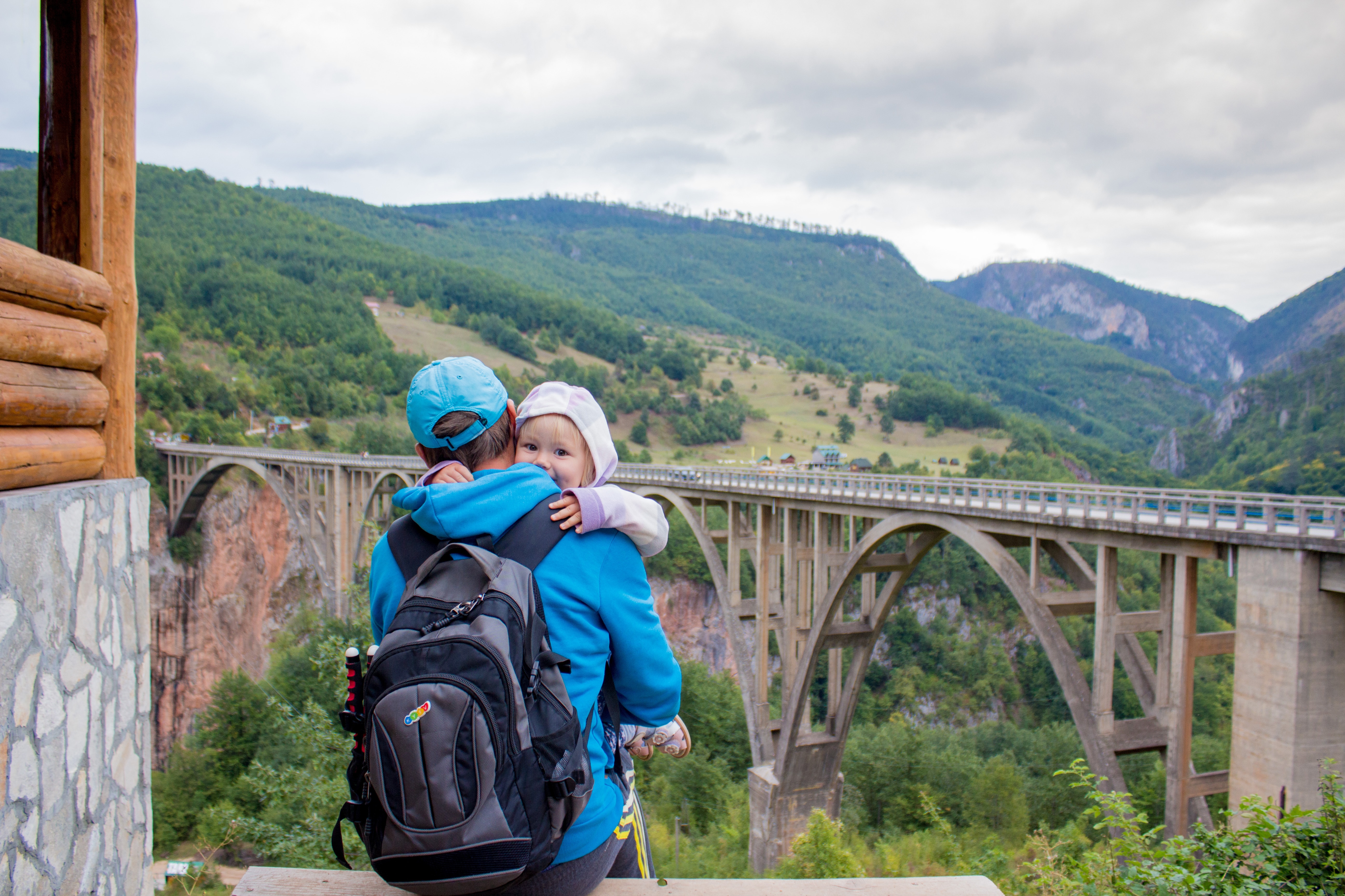 dad carrying child, looking at a bridge and his carry on bag