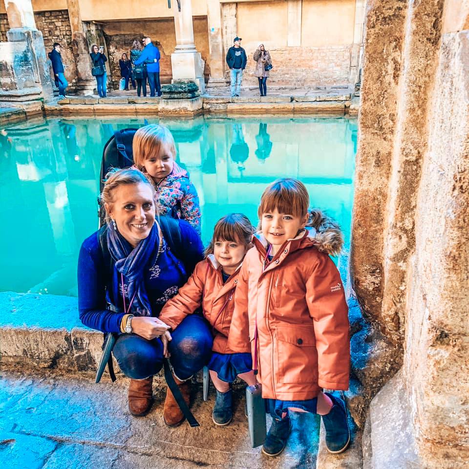 A family sitting in front of the Roman Baths in Bath. 