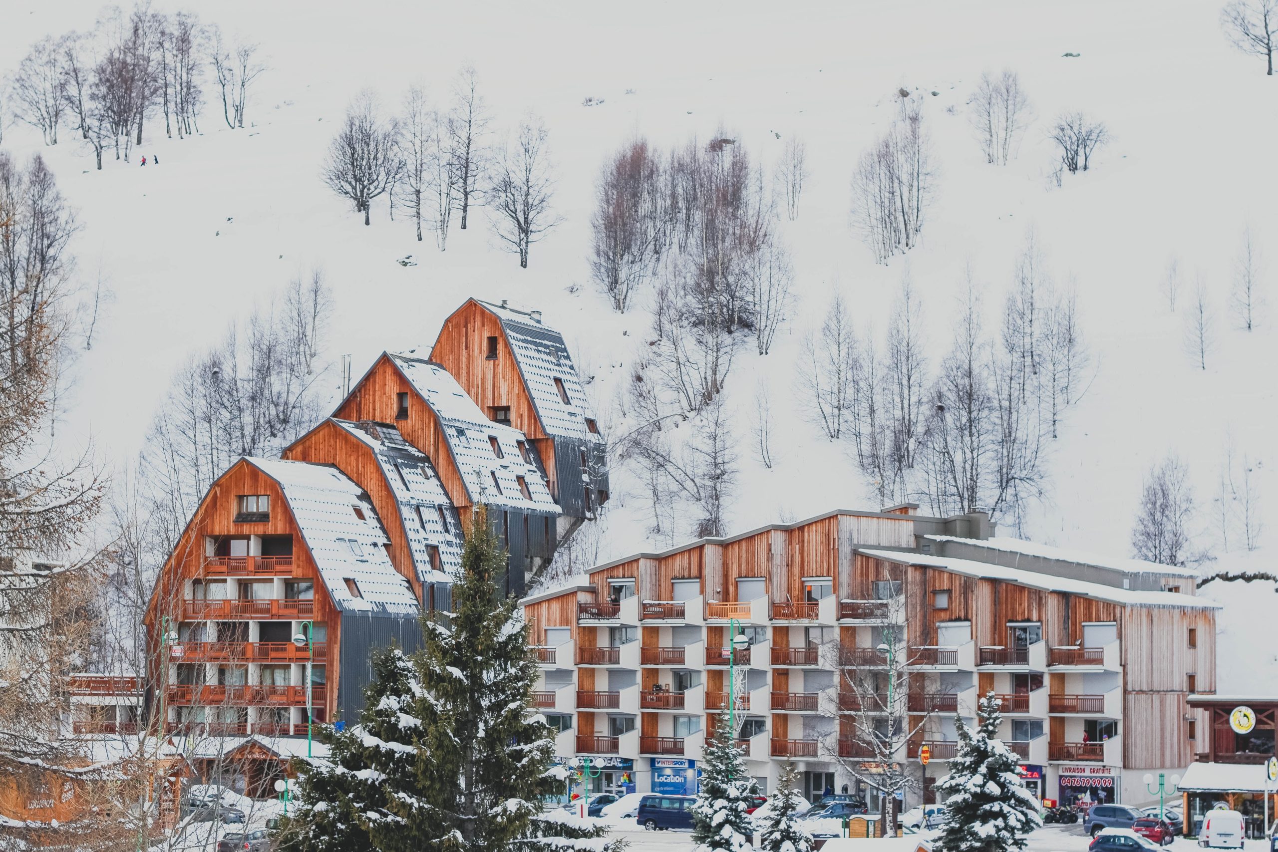 picture os snow covered multi story hotel built in the side of a mountain with balconies covered in wood