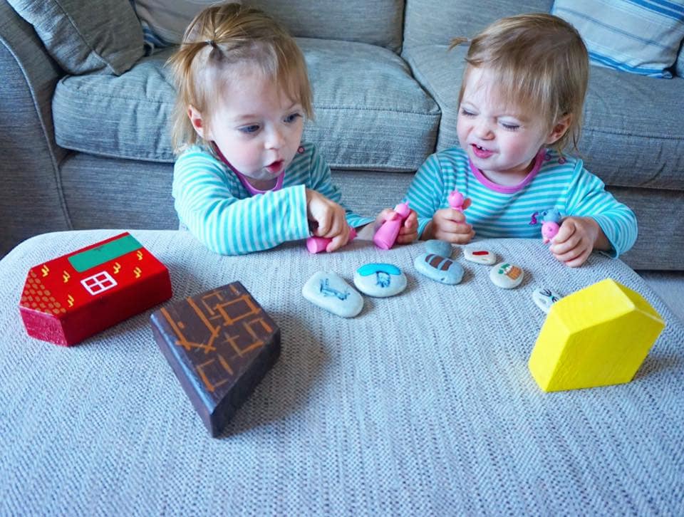 Toddlers acting out the three little pigs with houses and three little wooden pigs