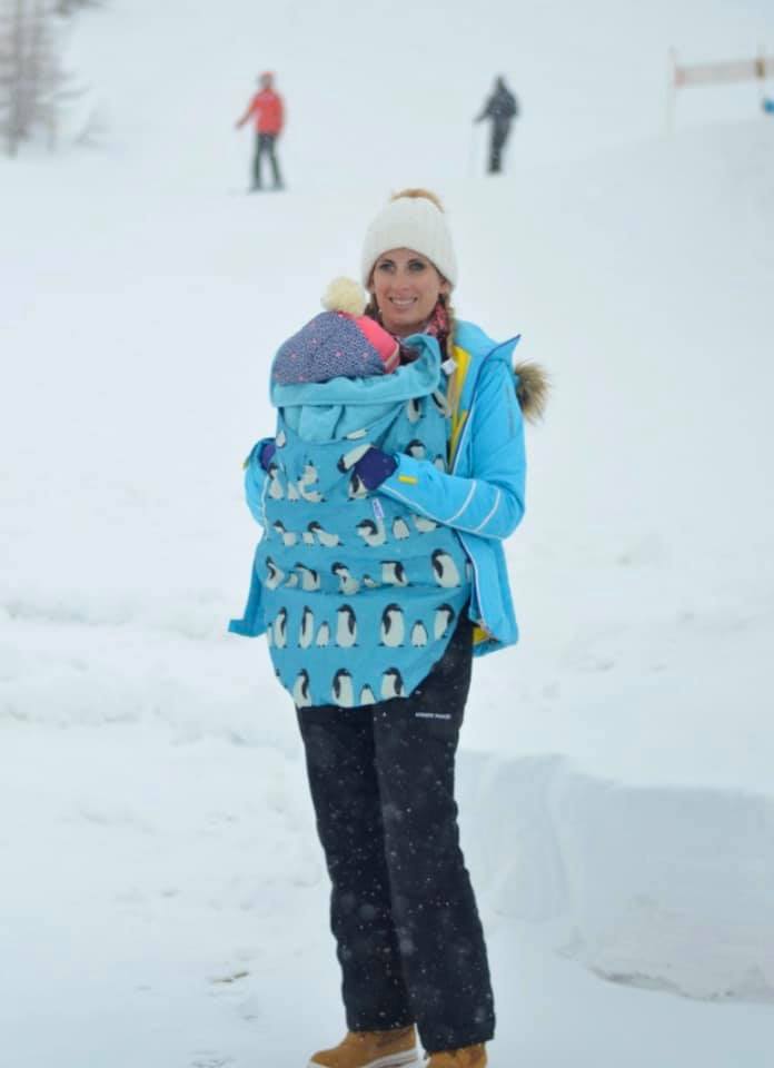 Mummy holding a baby in a snow sling whilst standing in snow