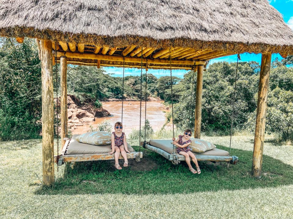 twin girls wearing sunglasses on swing beds along side a river