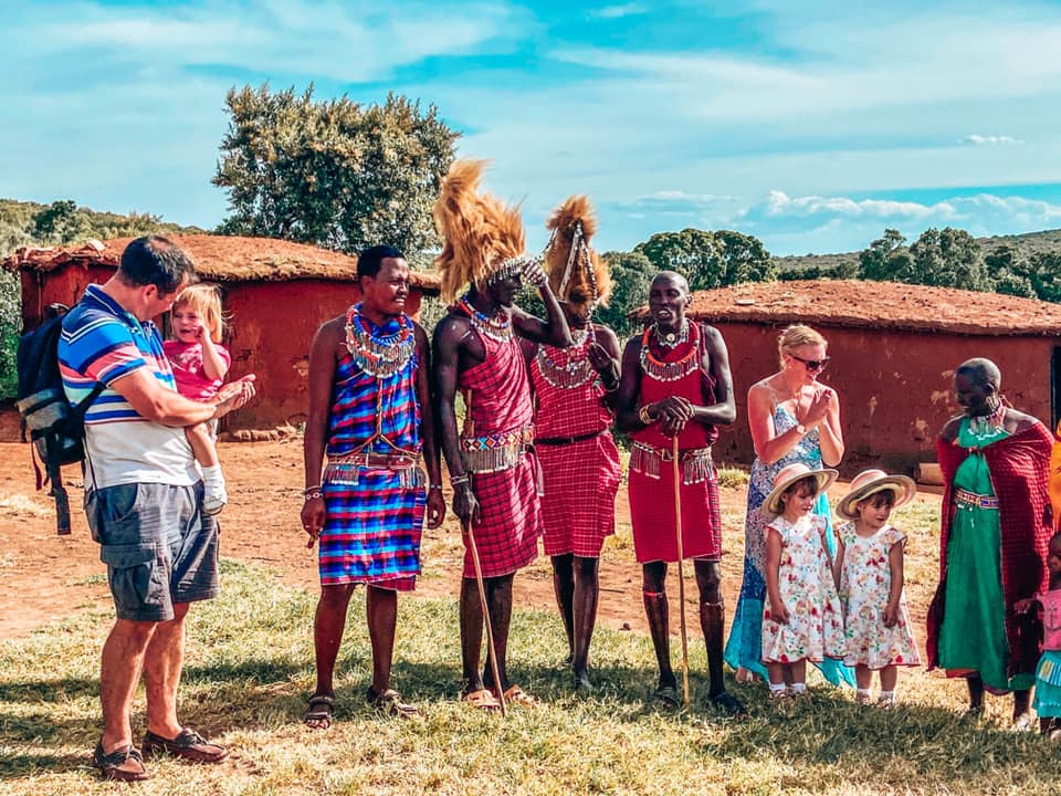 family surrounded by residents of Maasai Mara with Kids maasai dancers