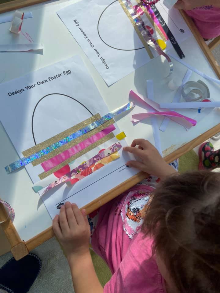 child sticking strips of paper onto an outline of an egg