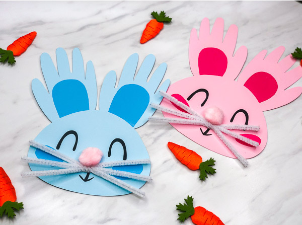 two paper bunnies in blue and pink with ears made out of cut out hand prints