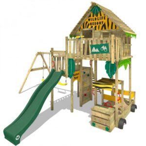 A large wooden playhouse high up on stilts with a slide coming out of the playhouse and a sandpit underneath