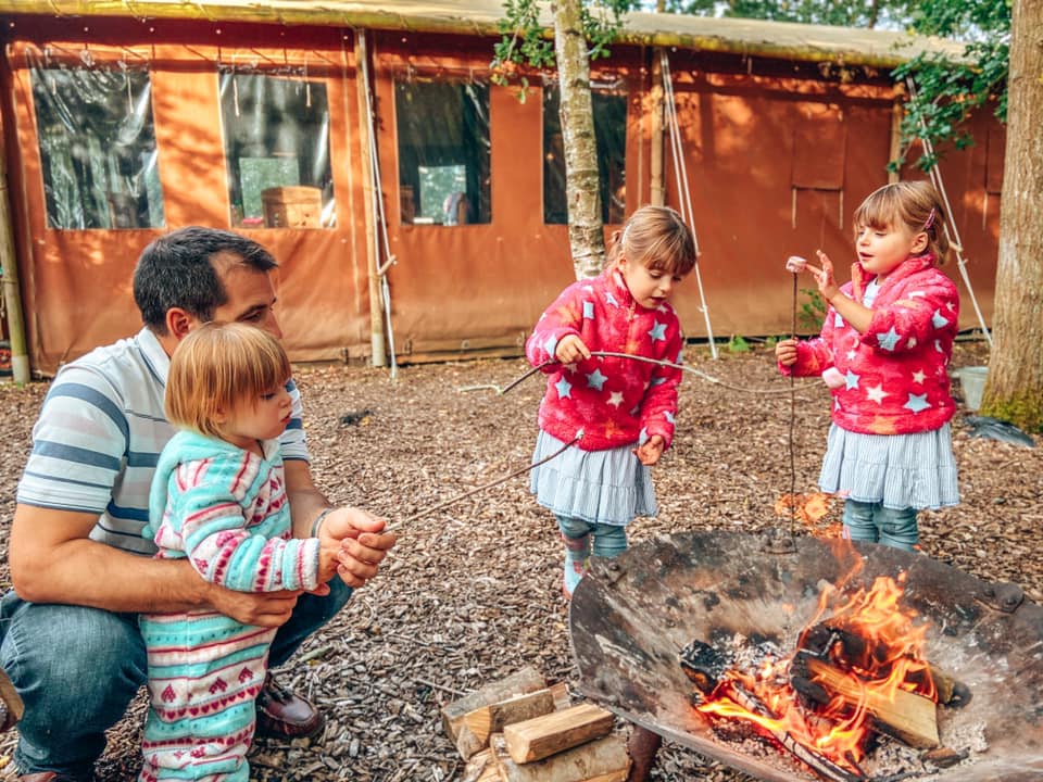 three children and a daddy around the campfire toasting marshmallows