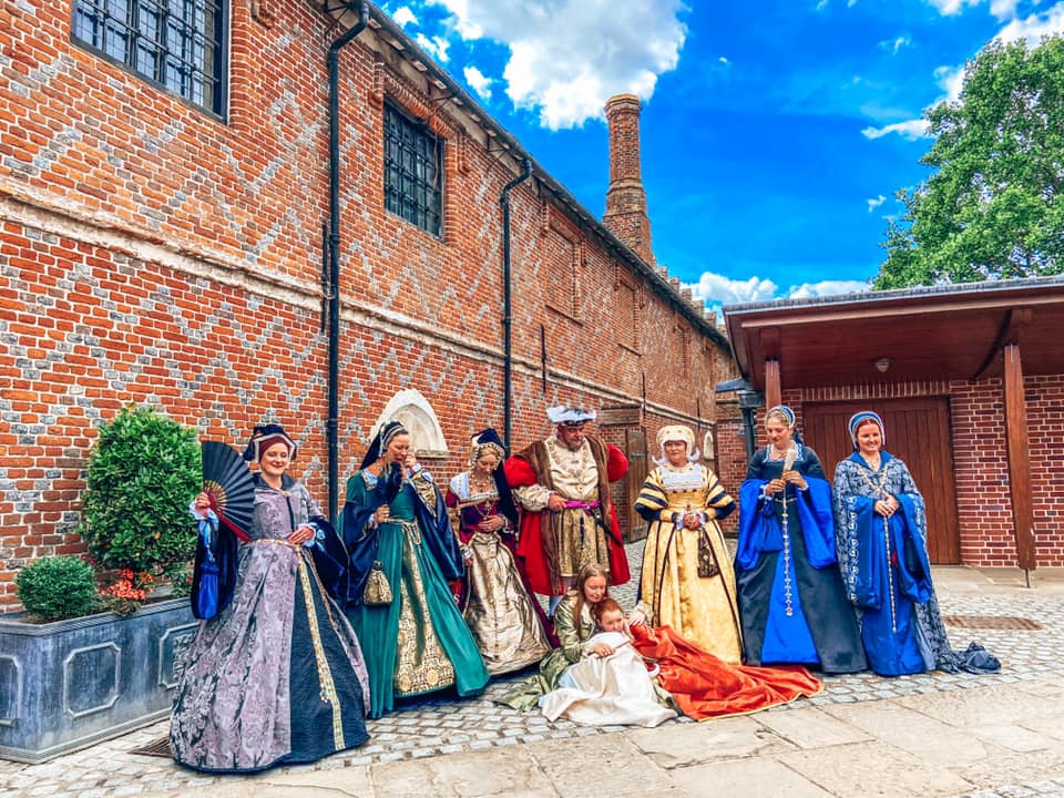 nine people dressed in elegant tudor costumes with king henry the VIII at Layer Marney tower in Essex