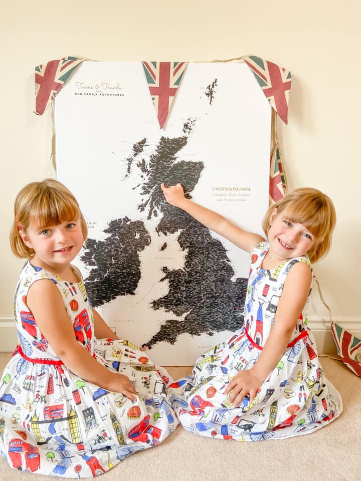 Trip Map Pin Map learning up against the wall with two girls in London dresses smiling at the camera