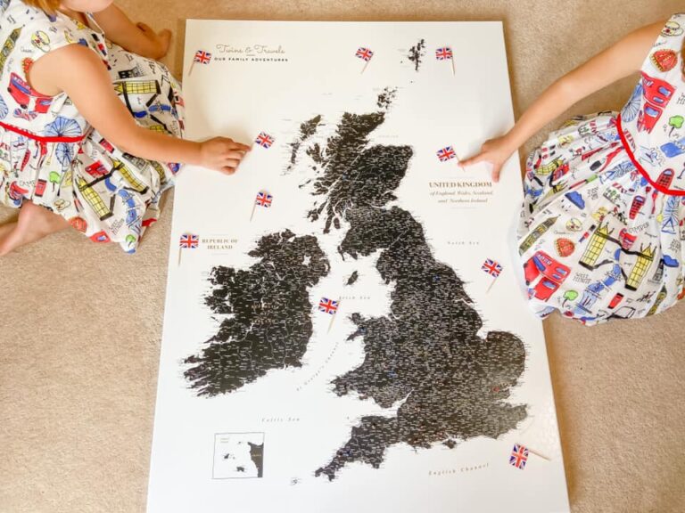 Map of the UK on the floor with two girls arms pointing at small UK flags
