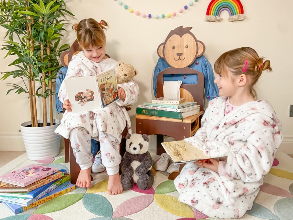 Two girls sitting on eco friendly wooden Mani Me chairs made in the shape of a bear and monkey