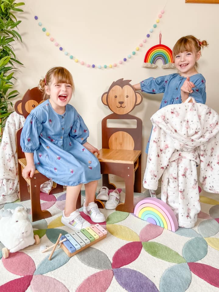 two girls laughing and leaning on their mama me wooden animal chairs