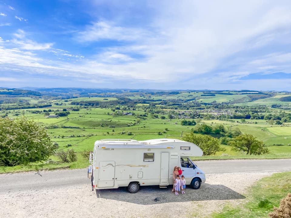 White campervan on top of a hill overlooking the Peak District