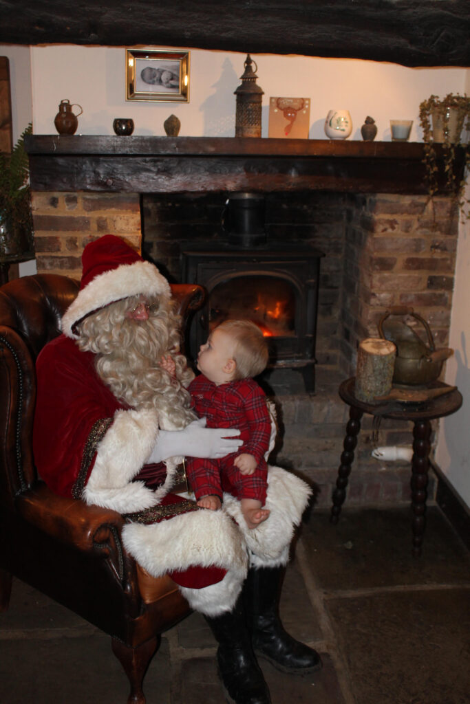 A little girl sat on Santa's knee in front of the fire place