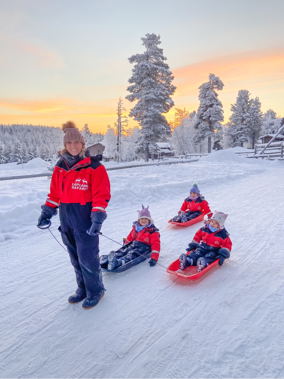 mum with three girls on sledges in Lapland