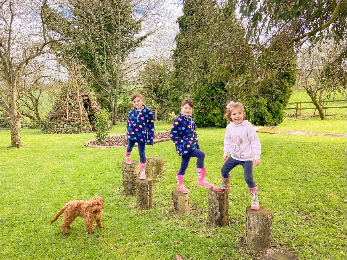 Classic Cottages Park Farm Cottage stepping logs with three girls playing on them