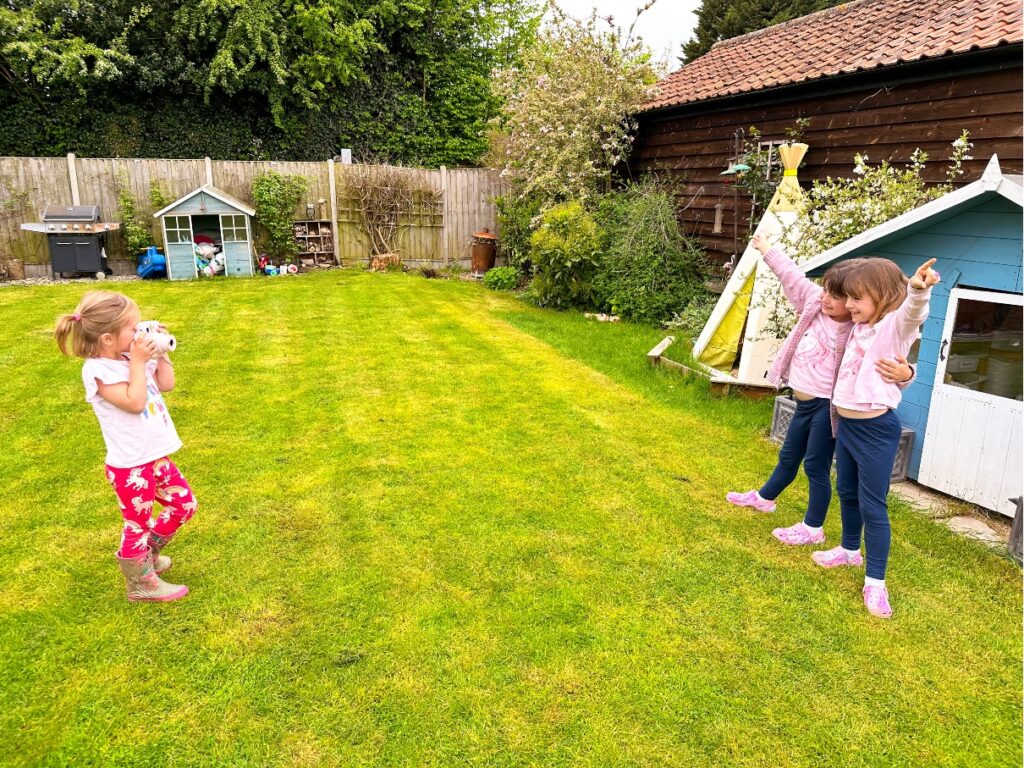 Young girl taking photo of two other girls in front of a play house with a Fujifilm Instax Mini 11 Instant Camera Photoshoot