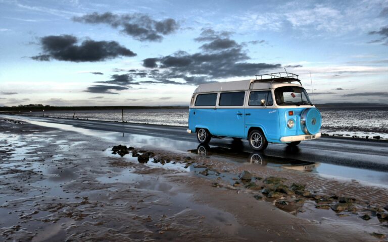 A blue camper van on a beach