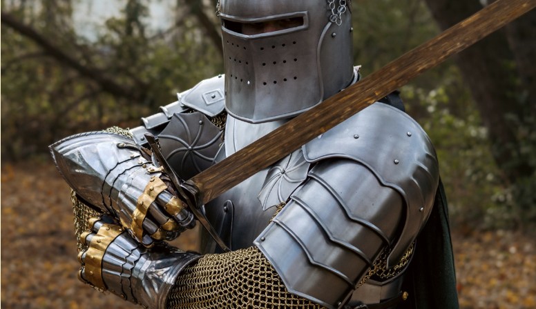 Armored medieval knight holding sword outdoors
