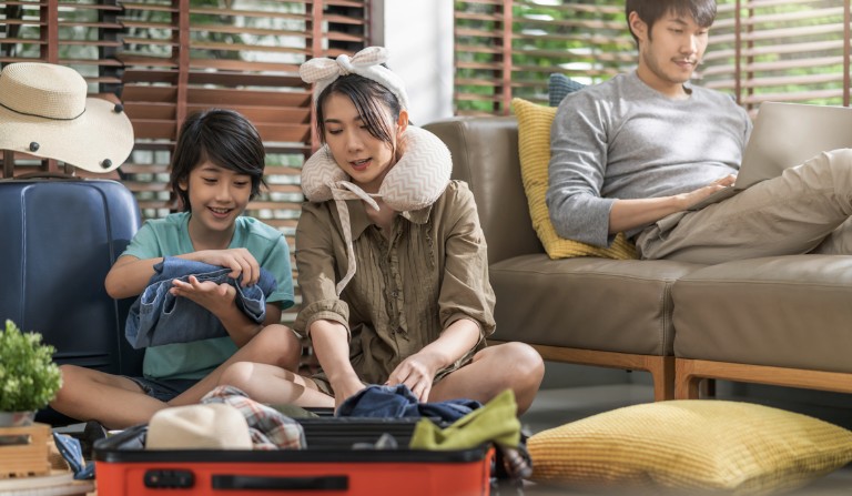 Family packing suitcase for vacation at home