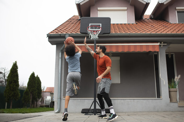 Father and son playing basketball in driveway