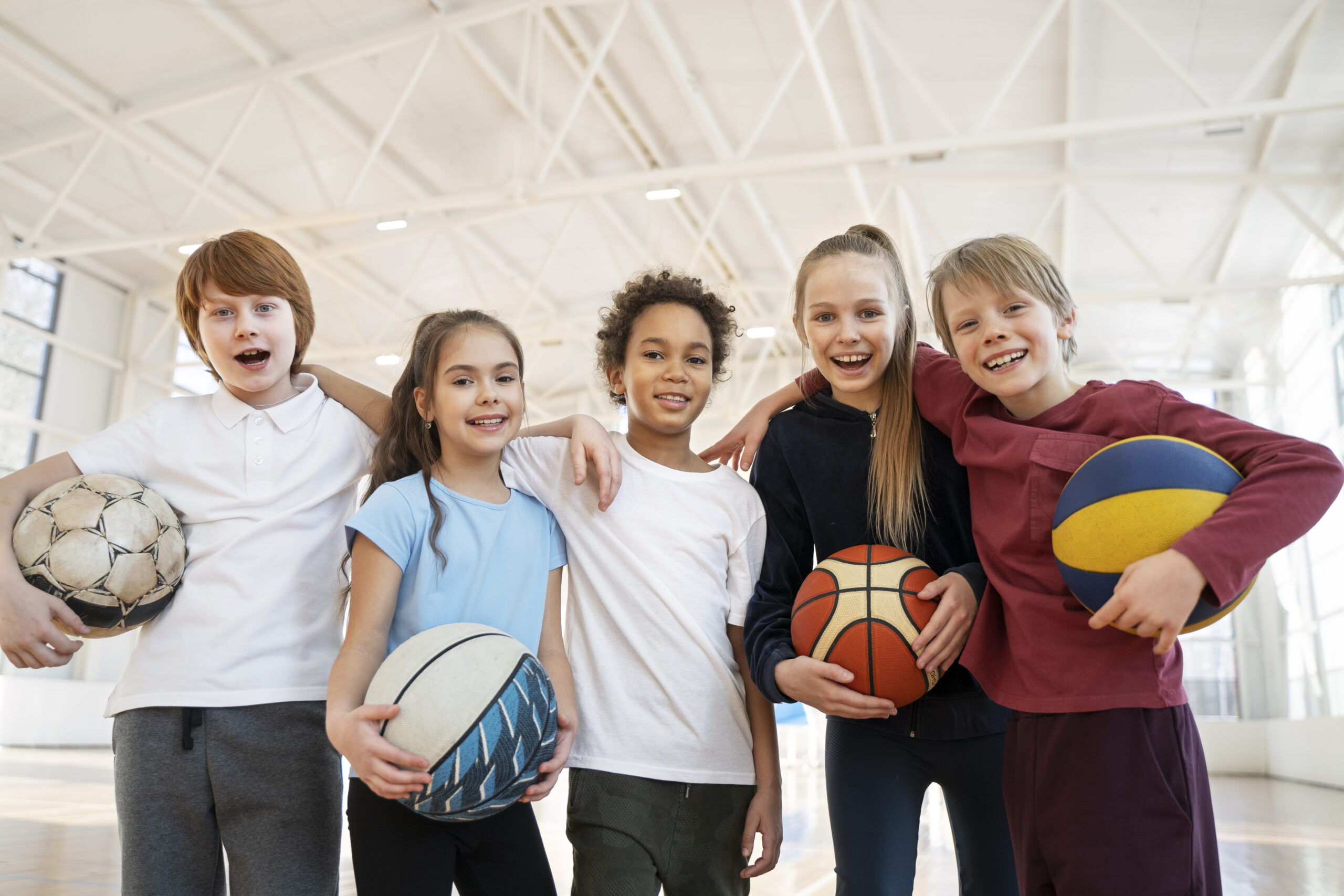 Kids sports team holding balls in gym