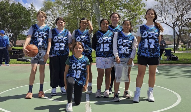 Youth basketball team posing on outdoor court